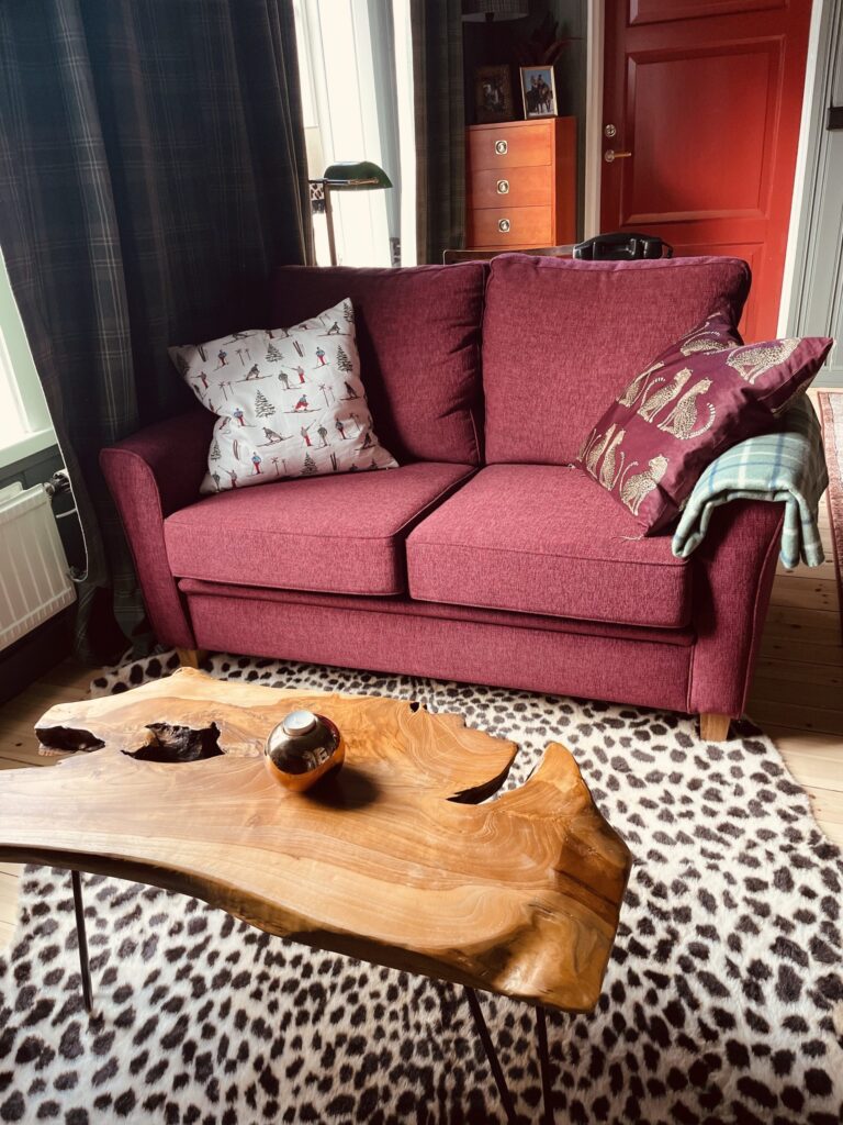 Röd soffa och ett soffbord av en trästock