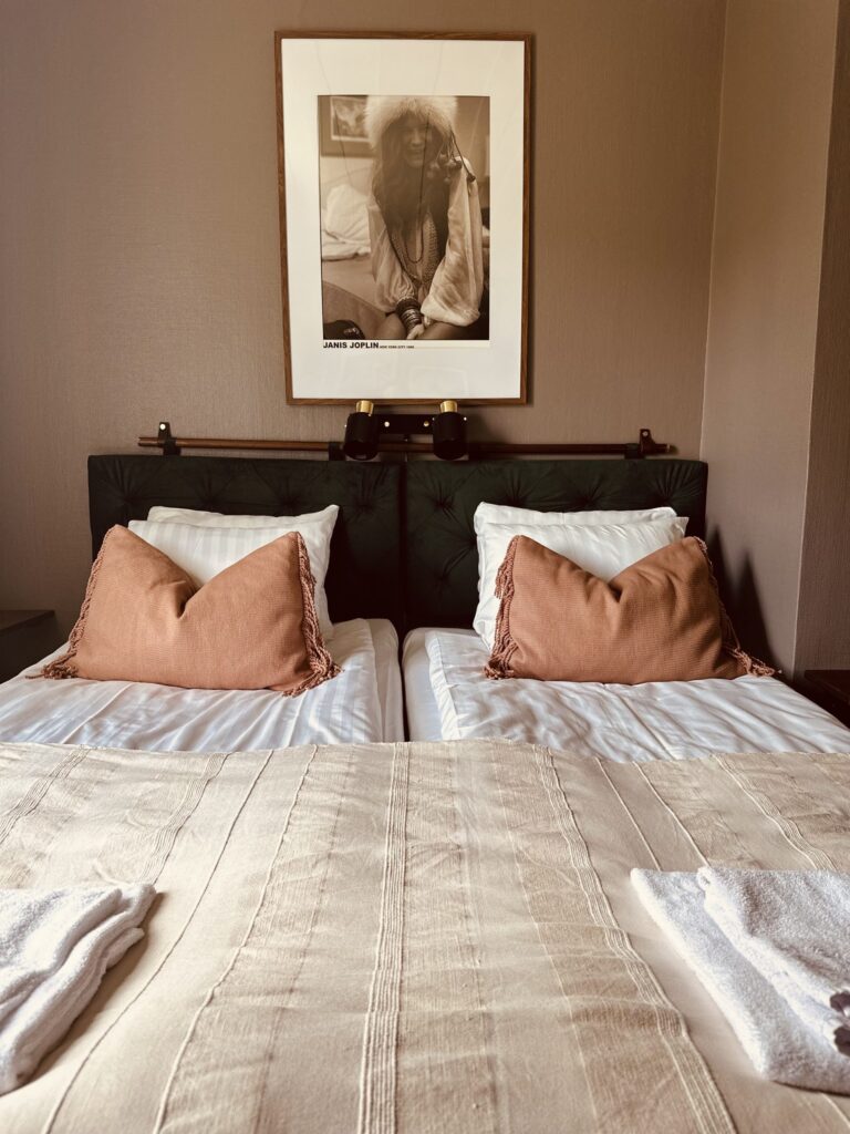 Två bäddade sängar med rosa kuddar under ett fotografi